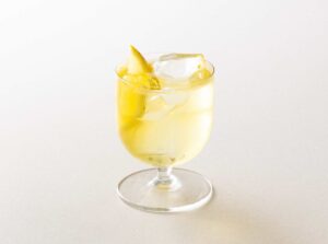 Un Sorbole spritz servito in un calice con una bottiglia di Sorbole sullo sfondo
