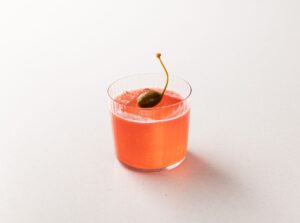 red è un cocktail a base sorbole, lamponi e pepe rosa, decorato con un cappero